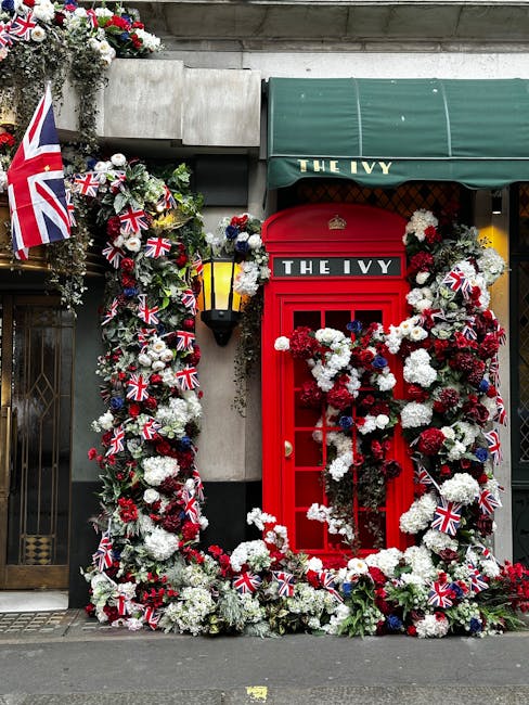 A vibrant floral display decorating the front entrance of The Ivy, featuring a large arch and frame densely covered with white, red, and deep pink flowers, including carnations and chrysanthemums. The